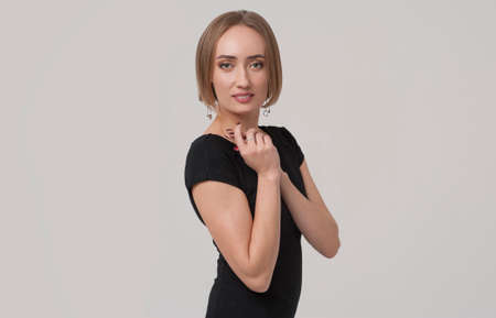 Young charming female manager or business woman wearing black outfit posing over grey background.の写真素材