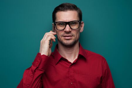 Portrait of a positive young man in glasses with phone