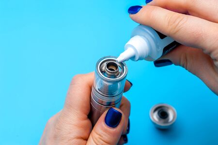 Close-up - female hands preparing device to vaping e-cigarette. New popular vaping device. Vapour,...