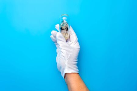 Hands in white gloves carefully hold light bulbの写真素材