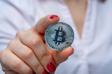 Young unidentified woman holding a bitcoin coinの写真素材