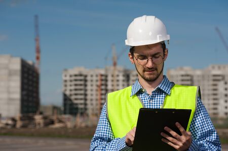 Portrait of Young Man Engineer In Green Vest With Planの写真素材