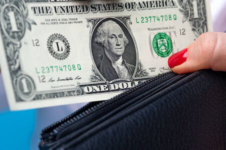 Close-up of a womans hands putting banknotes of one dollar