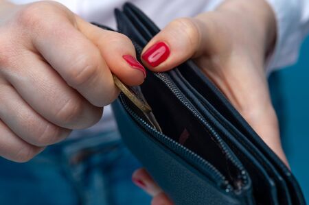 Close-up female hands put an iron coin in a purse