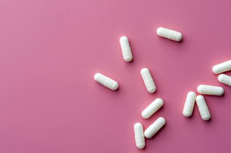 Close-up of white pills lie on a pink surfaceの写真素材