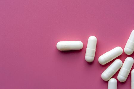 Close-up of white pills lie on a pink surfaceの写真素材