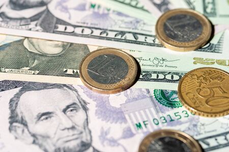 Dollar bills and coins lie next to each otherの写真素材