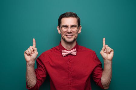 Portrait of a cute young man showing fingers on a green backgroundの写真素材