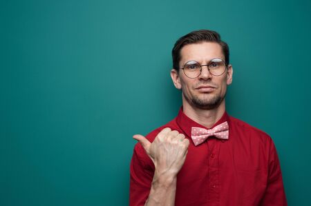 Portrait of a cute young man showing finger on a green backgroundの写真素材