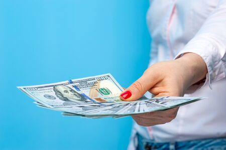 Hands of a young unidentified woman with pack of dollars