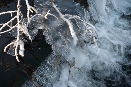 Top view of a high rapid with frozen ice floes and water pouring under them. The concept of a sharp cooling and changing seasonsの写真素材