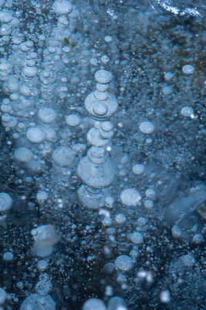 Top view white air bubbles floats from the bottom of the river and froze under a layer of ice. The concept of the onset of winter or the beginning of spring. Copyspaceの写真素材