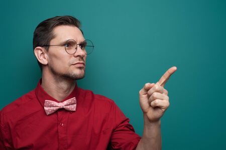 Portrait of a cute young man showing finger on a green backgroundの写真素材