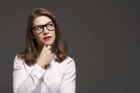 Young pensive woman with stylish glasses and red lipsの写真素材