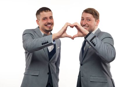 Two young funny men in formal clothes show heartの写真素材