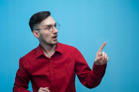 Shocked young man in glasses and a burgundy shirtの写真素材