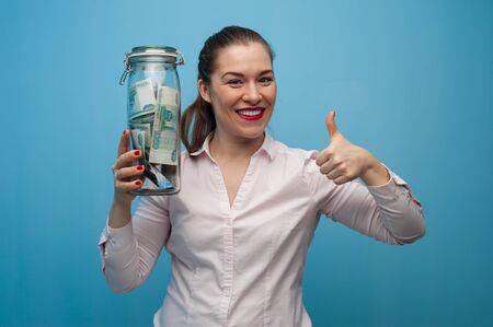 Young charming woman holds a jar with moneyの写真素材