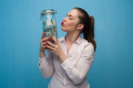 Young charming woman holds a jar with moneyの写真素材