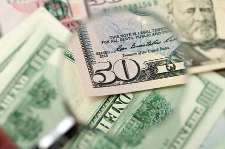 Magnifying glass lies on scattered dollarの写真素材
