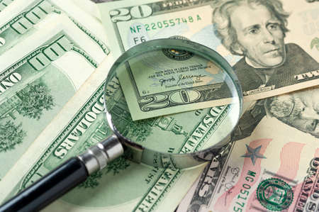 Magnifying glass lies on scattered dollarの写真素材