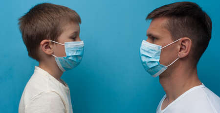 Father and son wearing protective medical mask looking to each other.の写真素材