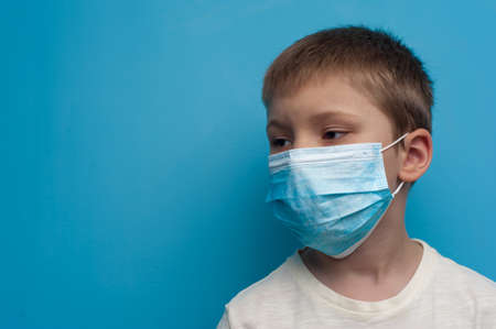Side portrait of child boy wearing a medical mask. Flu epidemic, dust allergy, protection against virus.の写真素材