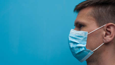 Side portrait of young woman wearing a medical mask. Flu epidemic, dust allergy, protection against virus.の写真素材