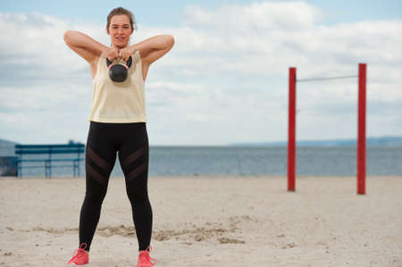 Woman weightlifting kettlebell weight at outdoor fitness gym.の写真素材
