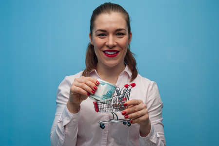 Young woman with a toy grocery basket with a bundle of rubles in her hands.の写真素材