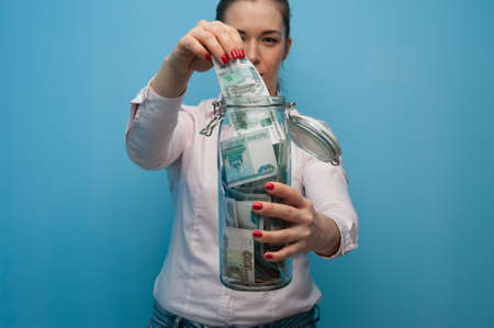 Young charming woman holds a jar with moneyの写真素材