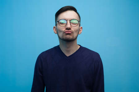 Portrait of young positive guy wearing casual clothes posing on blue background.の写真素材