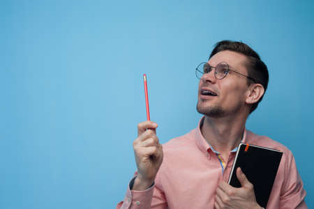Portrait of young man wearing glasses standing with pen and notebookの写真素材
