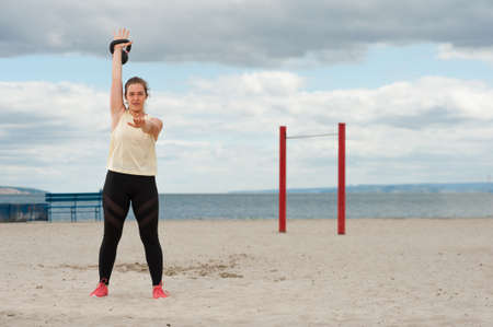 Woman weightlifting kettlebell weight at outdoor fitness gym.の写真素材