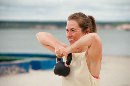 Woman weightlifting kettlebell weight at outdoor fitness gym.の写真素材