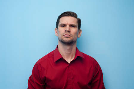 Portrait of a pensive serious young man in a shirt on a blue background.の写真素材