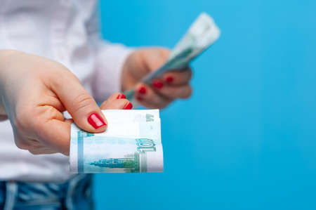 Hands of a young unidentified woman holding a pack of russian rubles