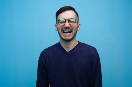 Portrait of young positive guy wearing casual clothes posing on blue background.の写真素材