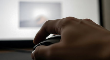 Close up of a man's hand using a computer mouse at homeの素材
