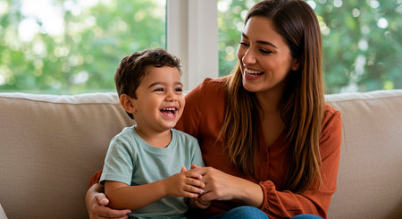 Portrait of happy mother and son sitting on sofa in living roomの素材