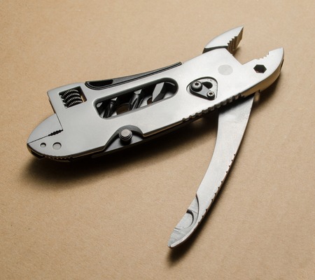 Multitool, pocket knife, pliers on a brown backgroundの写真素材