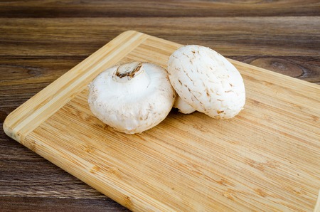 Field mushrooms on a cutting board on a wooden tableの写真素材