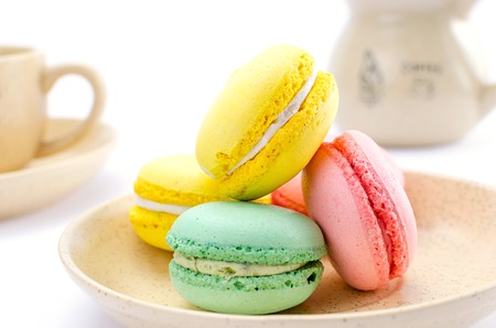 Multicolored macaroons on a saucer with the service on a white backgroundの写真素材