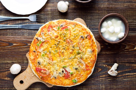 Rustic pizza with salami, mozzarella, olives and basil top view with copy space on a wooden tableの写真素材