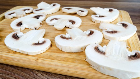 Sliced mushrooms on a cutting board on a wooden tableの写真素材