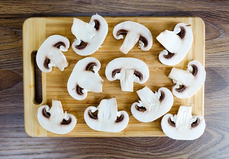 Sliced mushrooms on a cutting board on a wooden tableの写真素材