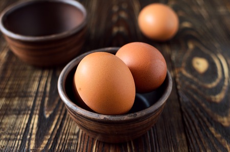 Fresh farm eggs in the bowl on a wooden rustic background