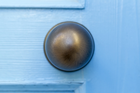 A brass door handle on a wooden blue doorの写真素材
