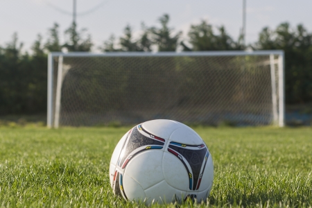 Soccer ball in Goal net with green grass fieldの写真素材