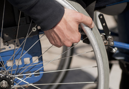 Close-up of male hand on wheel of wheelchair