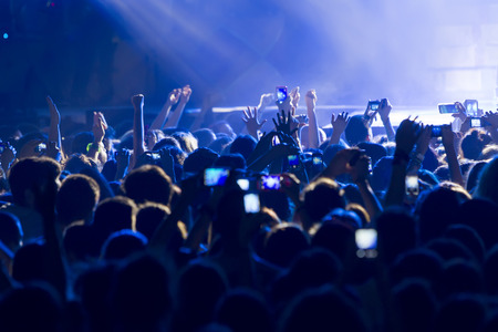 People taking photographs with touch smart phone during a music entertainment public concert 